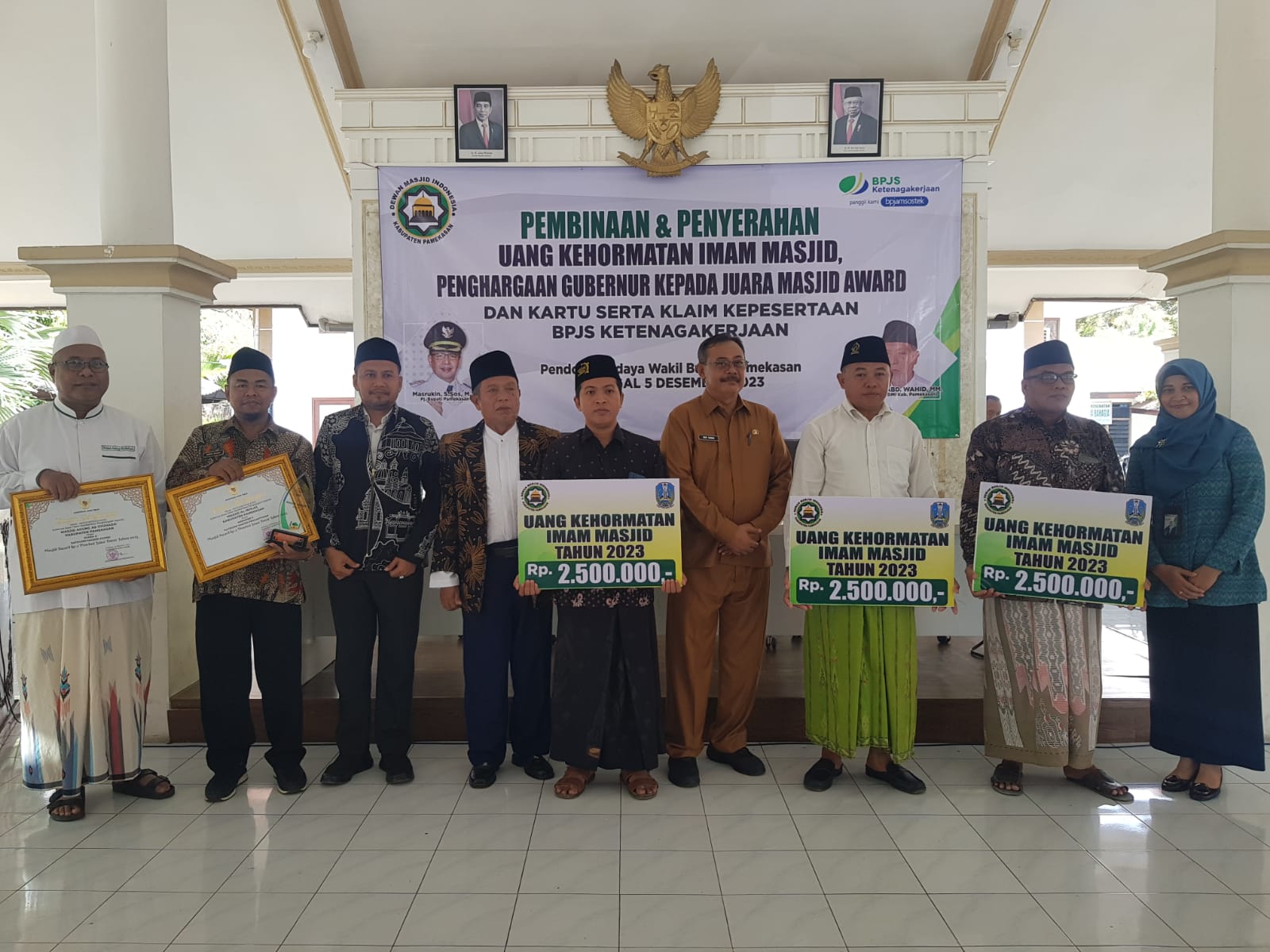 LAYANAN: Pimpinan BPJS Ketenagakerjaan Pamekasan Anita Ardhiana, Sekda Pamekasan Ach. Faisol dan Kepala Kemenag Pamekasan Mawardi foto bersama para imam masjid setelah pemberian uang kehormatan.