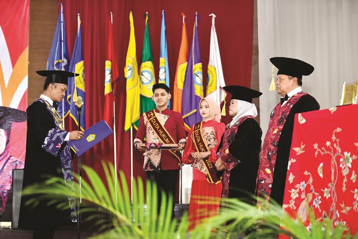 SAKRAL: Rektor UTM Safi&rsquo; mengukuhkan Guru Besar FH Prof. Dr. Deni Setya Bagus Yuherawan, S.H., M.S. dan Prof. Dr. Wartiningsih, S.H., M.Hum. di Gedung Pertemuan RP Moch. Noer Selasa (5/12).