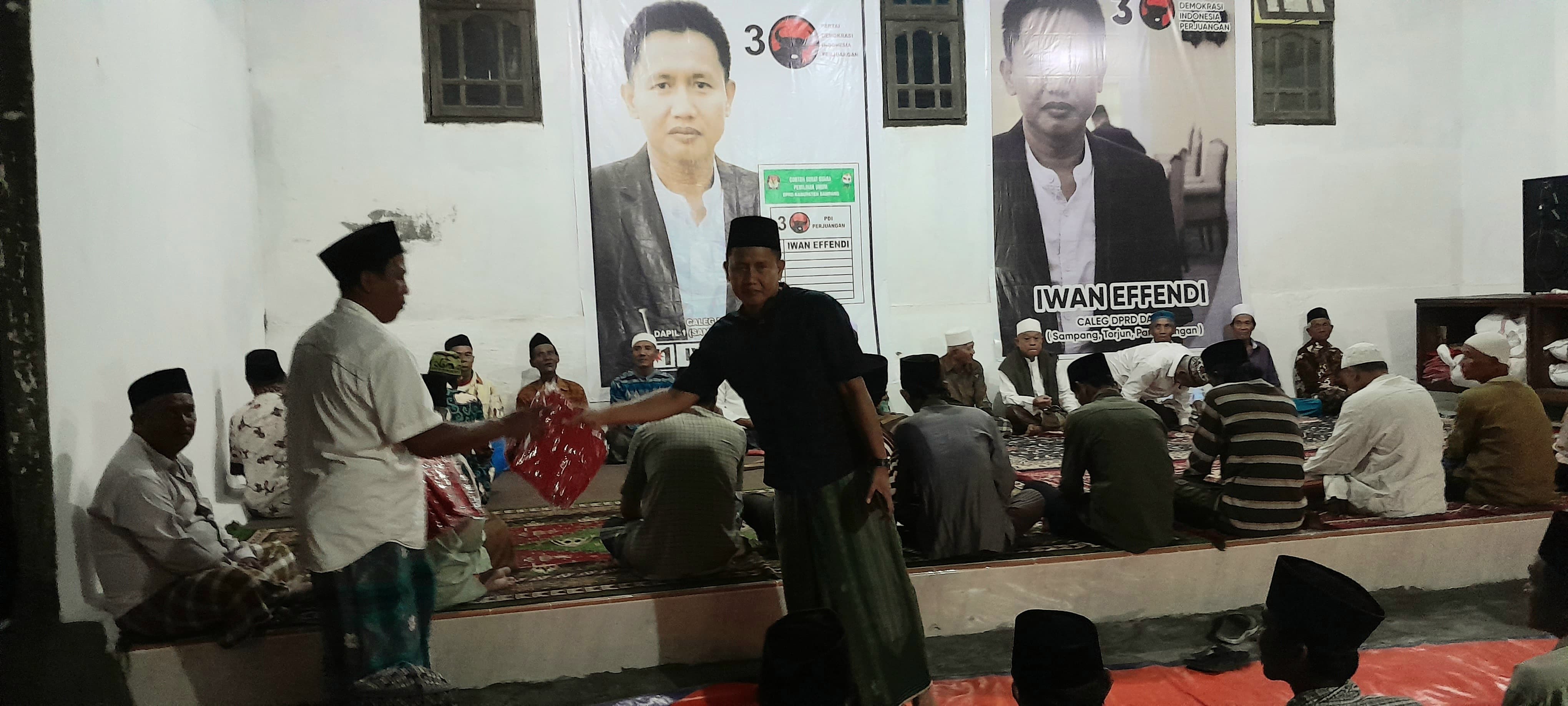 SIAP MEMENANGKAN: Bendahara DPC PDI Perjuangan Sampang Iwan Effendi (baju hitam) membagikan kaus partai di wilayah Kecamatan Kota Sampang. (PDIP SAMPANG UNTUK JPRM)