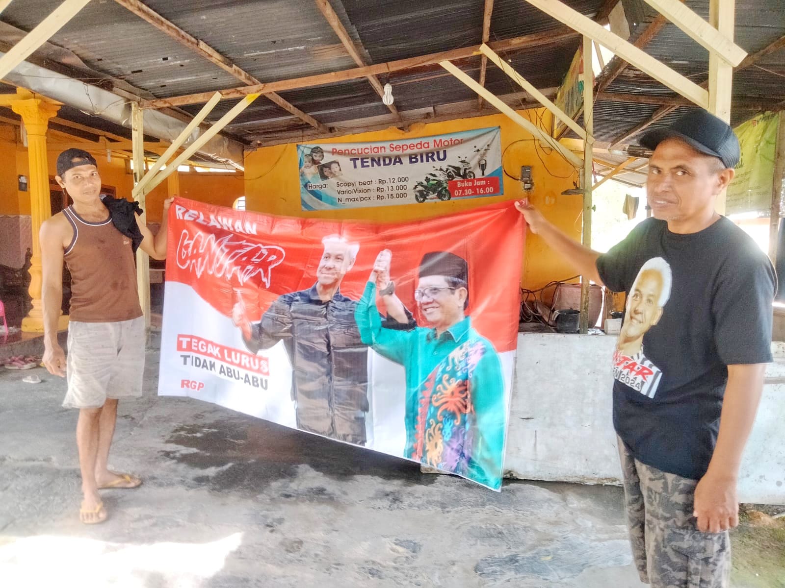 KAMPANYE: Warga Pamekasan memegang banner pasangan capres-cawapres Ganjar Pranowo dan Mahfud MD, Jumat (8/12). (NOER FAISAL UNTUK JPRM)