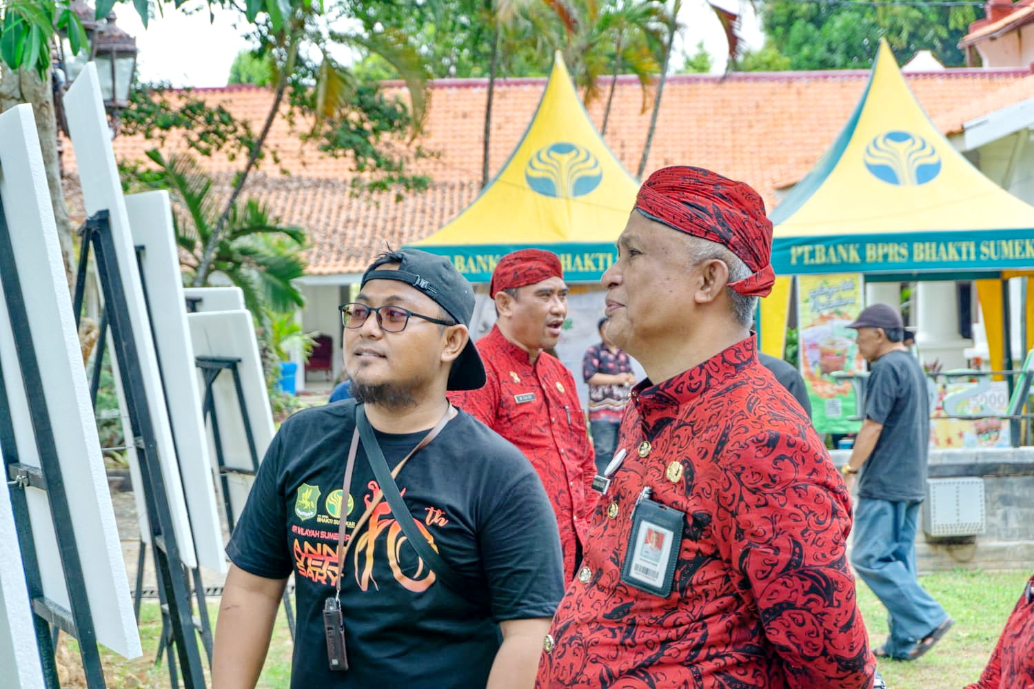 BERJALAN SUKES: Ketua KFI Sumenep Isman Budi Raharjo (berkacamata) saat mendampingi Kadisbudporapar Mohamad Iksan saat melihat karya foto yang dilombakan di area Keraton Sumenep pada Jumat (8/12).