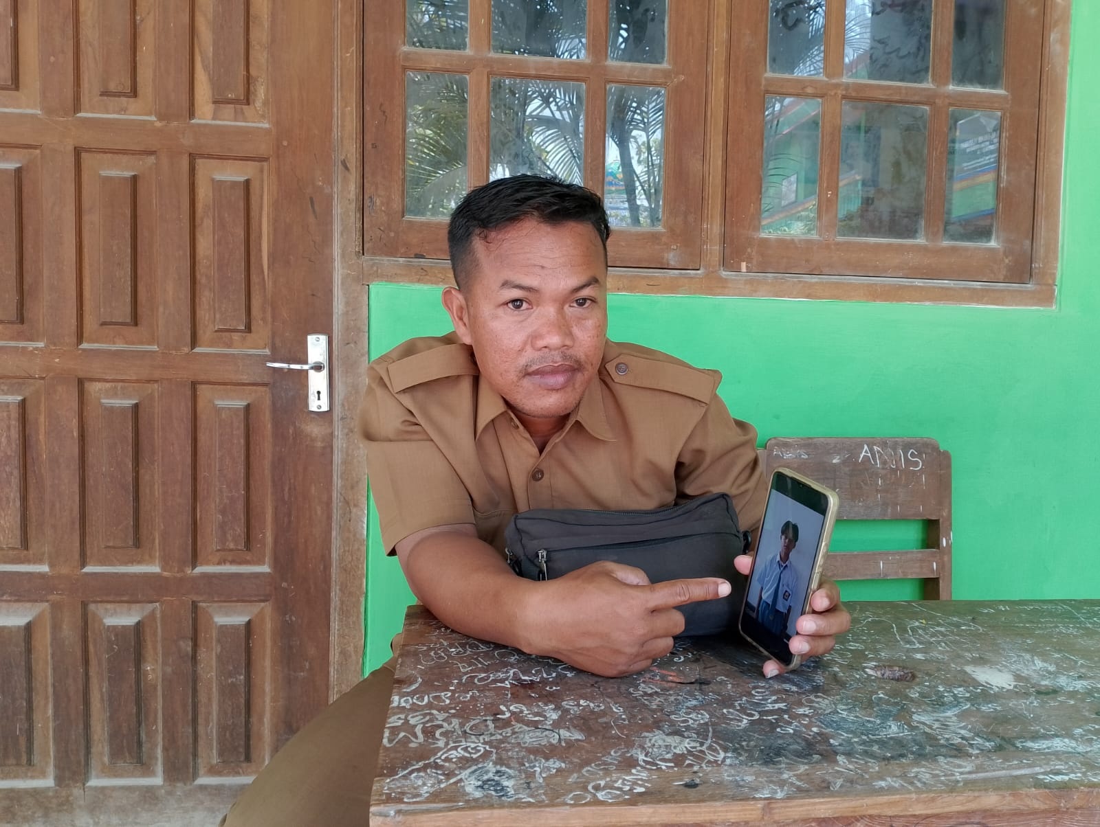 PULANG SEKOLAH: Guru sejarah MA Al-Falah Tlanakan, Pamekasan, Abd. Salam menunjukkan foto Fajrul Amar, siswa yang meninggal dalam kecelakaan, Senin (11/12). (UBAIDILLAHIR RA&rsquo;IE/JPRM)