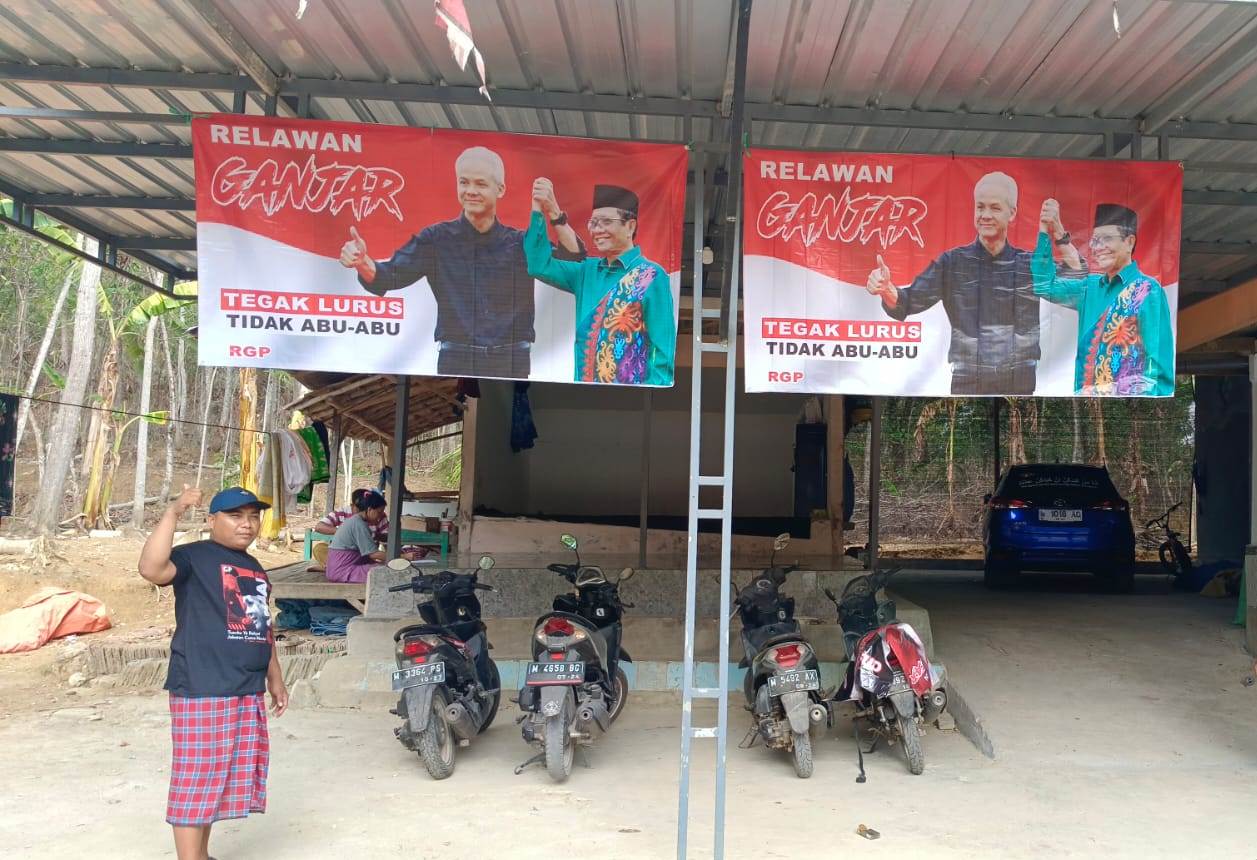 DUKUNGAN: Riadi, warga Dusun Tacempa, Desa Plakpak, Kecamatan Pegantenan, berfoto&nbsp;setelah memasang banner Ganjar-Mahfud, Senin (11/12). (RELAWAN GANJAR UNTUK JPRM)