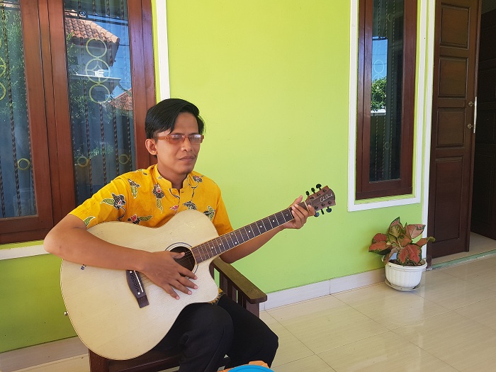 INSPIRATIF: Imron Wicaksono memainkan gitar di rumahnya, Desa Buddih, Kecamatan Pademawu, Pamekasan, Selasa (12/12). (LAILIYATUN NURIYAH/JPRM)