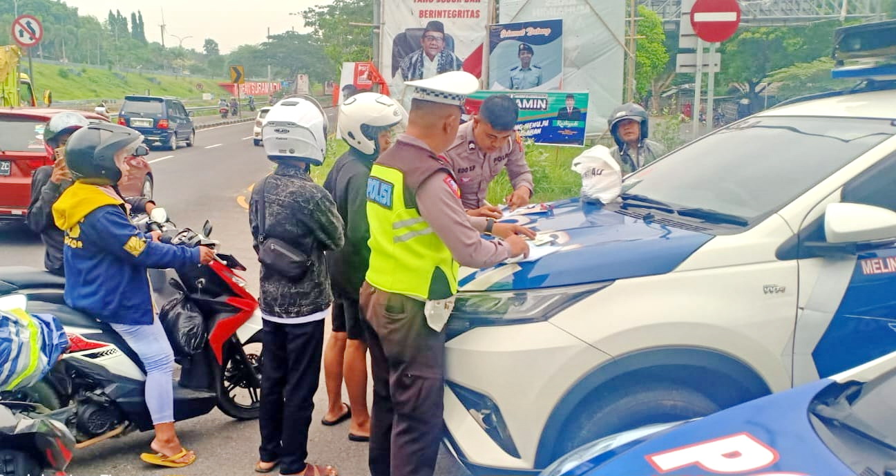 DITILANG: Petugas memberikan sanksi tilang kepada pengendara sepeda motor yang terjaring dalam razia karena melintas di jalur mobil di akses Jembatan Suramadu, Jumat (15/12).