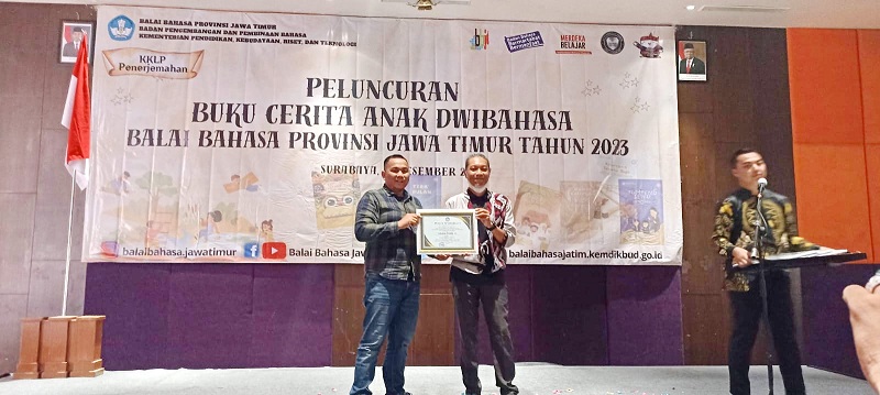 APRESIASI: Lukman Hakim AG (kiri) menerima penghargaan dari Koordinator Penyunting Buku Cerita Anak Dwibahasa Jawa Timur 2023 Awaludin Rusiandi di Hotel Mercure Grand Mirama Surabaya, Selasa (12/12).