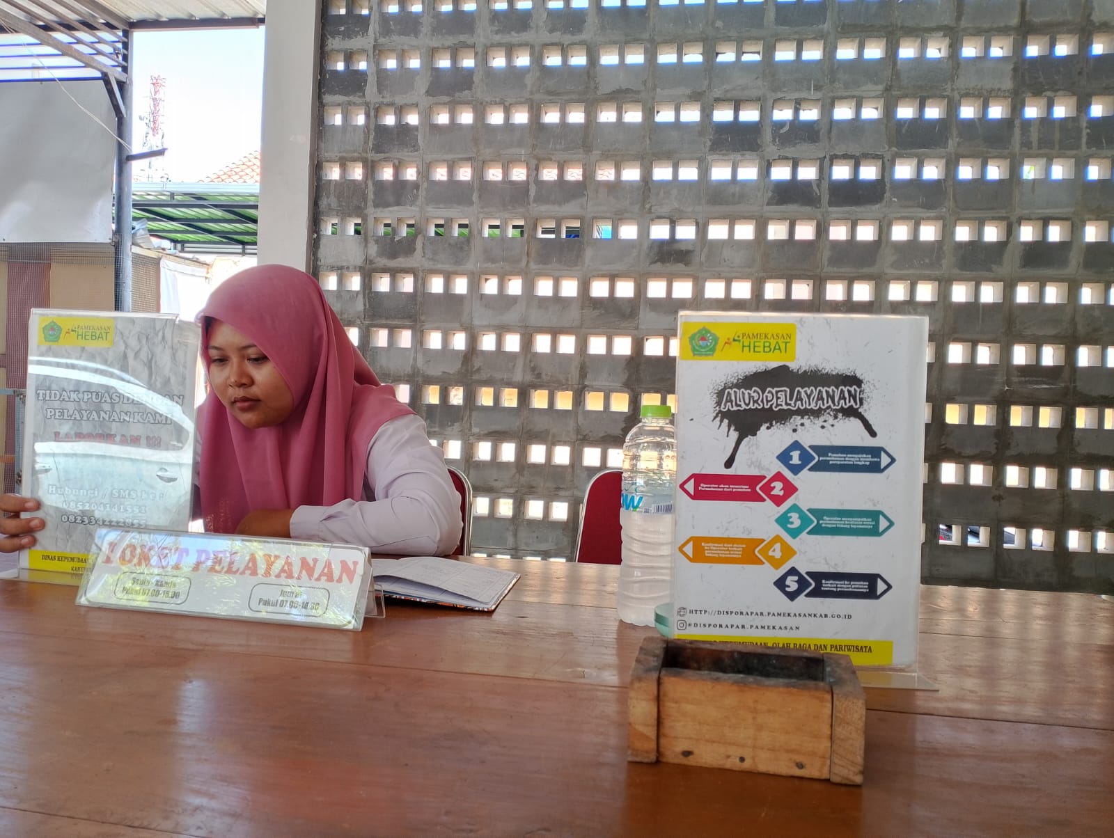 BERTUGAS: Karyawan Disporapar Pamekasan bertugas di ruang resepsionis, Rabu (20/12). (UBAIDILLAHIR RA&rsquo;IE/JPRM)