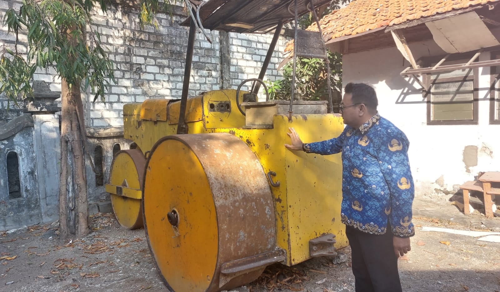 RUSAK: Salah seorang pegawai melihat kondisi alat berat milik pemerintah yang saat ini masuk daftar lelang di tempat penyimpanan milik Dinas PUPR Sampang, Selasa (19/12). (JUNAIDI PONDIYANTO/JPRM)
