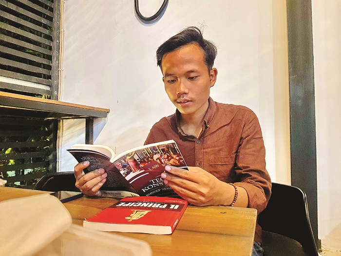 PENGETAHUAN: Muhammad Romli membaca buku di Kafe Nirwana Jalan KH Amin Jakfar, Kelurahan Gladak Anyar, Pamekasan, Jumat (22/12). (LAILIYATUN NURIYAH/JPRM)