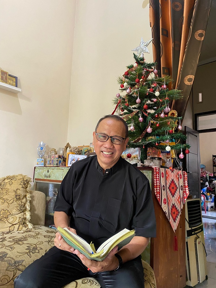 TOLERANSI: Pdt Zefanja Indrawan Walujo memegang Kitab Injil di rumahnya di Kelurahan Mlajah, Kecamatan Bangkalan, Selasa (26/12). (AYU LATIFAH/JPRM)