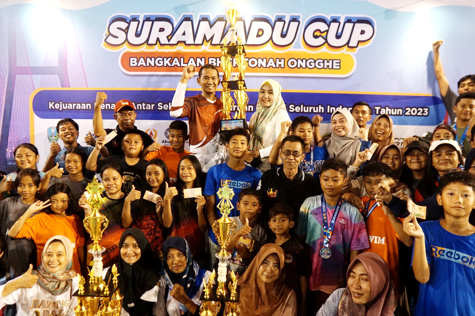 MEMBANGGAKAN: Kepala Dispora Bangkalan Akhmad Ahadiyan Hamid (pegang piala) berfoto bersama para atlet renang yang bertanding di Suramadu Cup, Minggu (24/12). (DISPORA UNTUK JPRM)