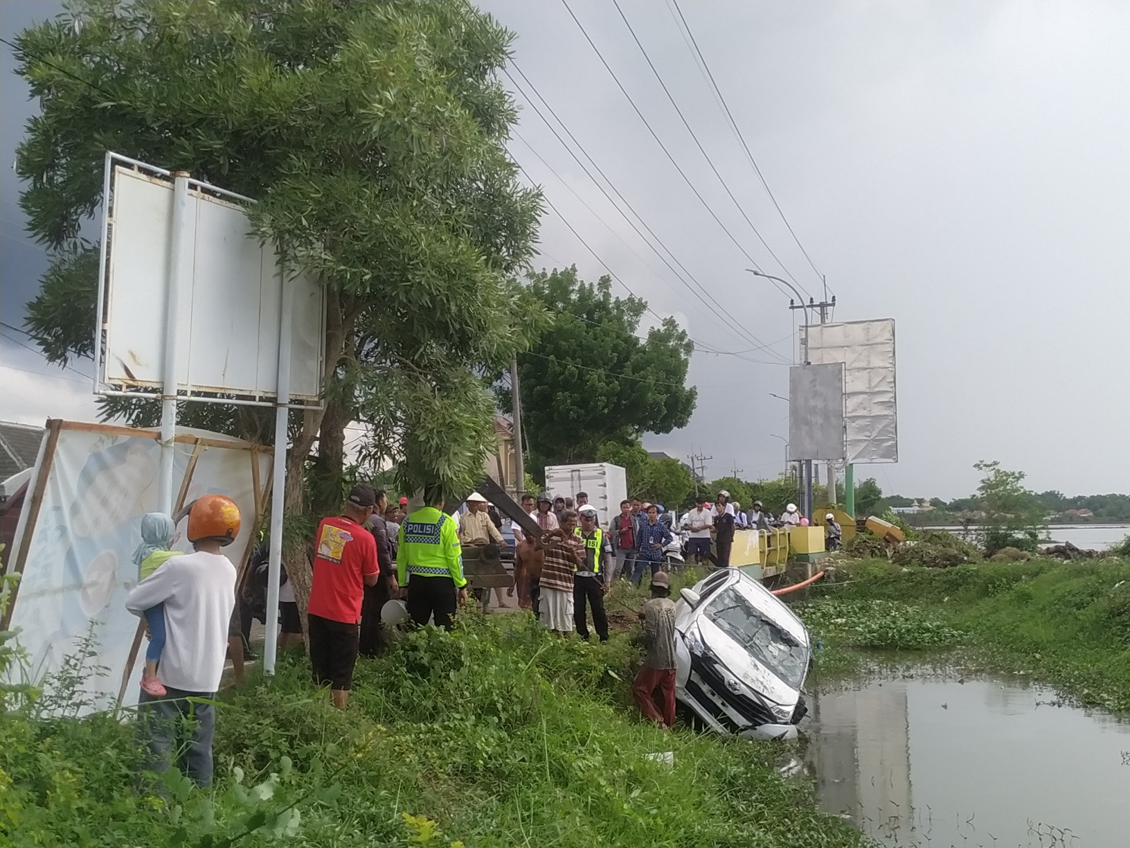 JADI TONTONAN: Warga menyaksikan proses evakuasi Totoya Calya yang mengalami laka lantas tunggal di Jalan Wiraraja, Desa Kolor, Sumenep, Jumat (29/12). (HERIVIYA YUVI/JPRM)