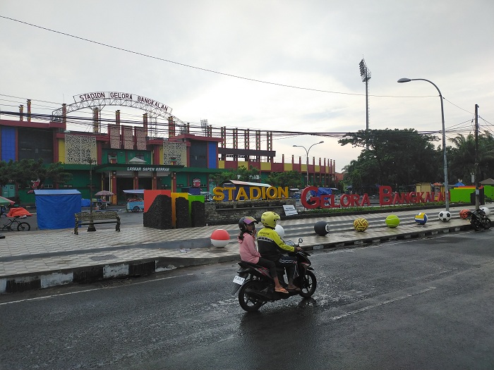 INSTAGRAMABLE: Pengendara melintas di dekat bola-bola beton yang terpasang di depan Stadion Gelora Bangkalan (SGB), Senin (1/1). (VIVIN AGUSTIN HARTONO/JPRM)