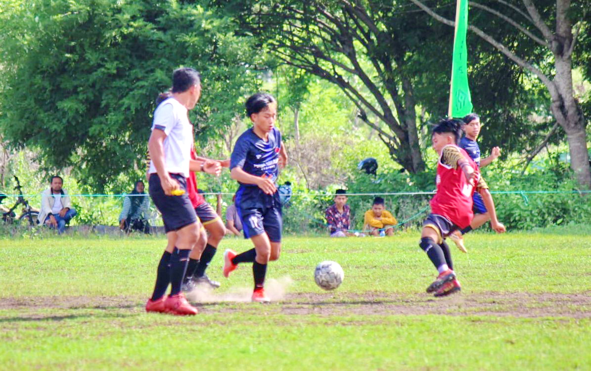 BERSAING: Pemain Putra Pahlawan dan PSG Gulbung berebut bola di Lapangan Sepak Bola Kampung Belanda, Desa Krampon, Kecamatan Torjun, Jumat (29/12/2023). (MOH. IQBAL AFGANI/JPRM)