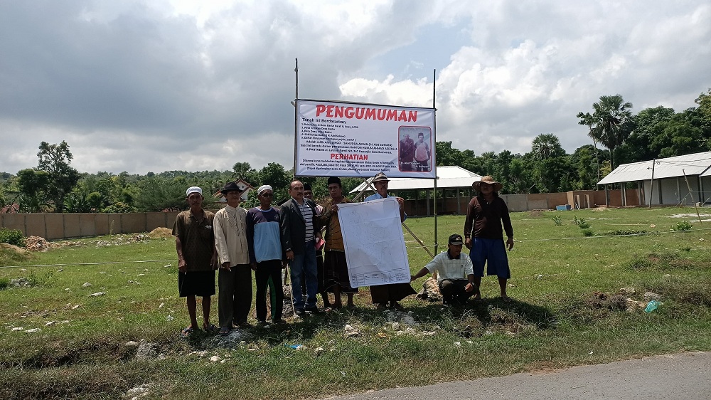 MENGGUGAT: Warga didampingi kuasa hukum Achmad Azizi memasang papan pengumuman pelarangan kegiatan di lahan yang dibangun Pasar Badur beberapa waktu lalu. (RIFKI UNTUK JPRM)