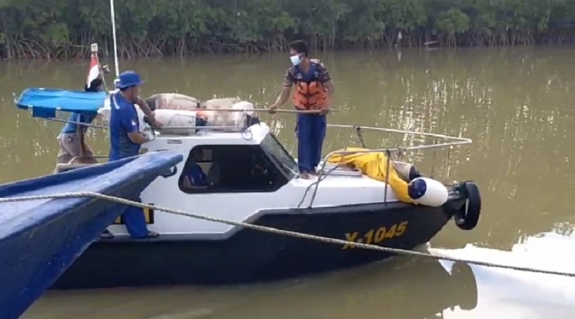 HATI-HATI: Petugas mengevakuasi mayat yang ditemukan di perairan Pulau Mandangin, Kamis (4/1). (POLRES SAMPANG UNTUK JPRM)