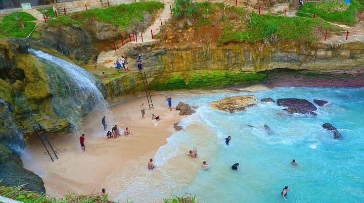 Pantai Banyu Tibo, keajaiban alam dengan air terjun yang mengalir ke laut. (@mbolangjatim untuk RadarMadura.id)