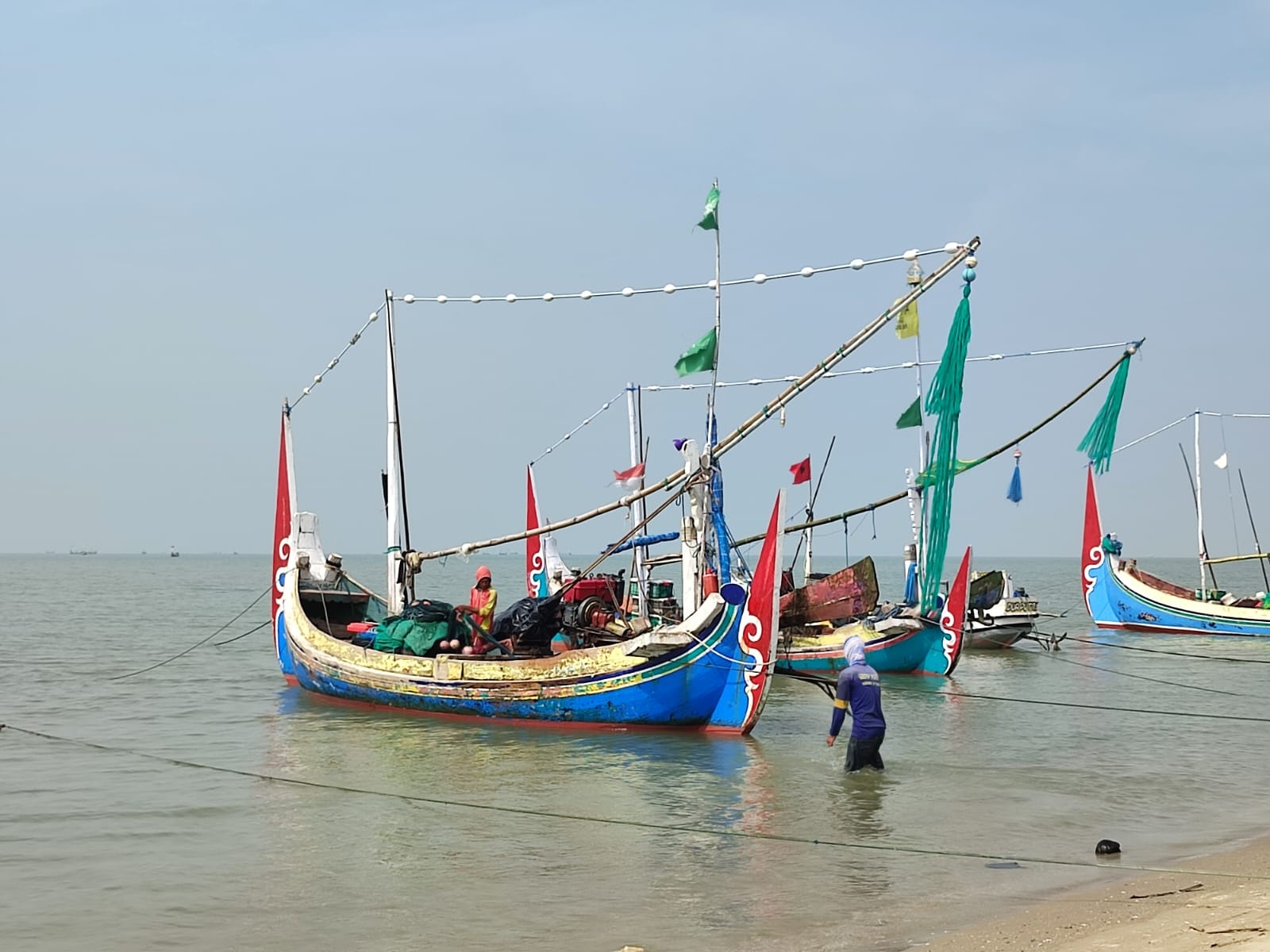 PULANG: Dua orang nelayan di Desa Tanjung, Kecamatan Pademawu, membereskan peralatan melaut, Selasa (9/1). (LAILIYATUN NURIYAH/JPRM)