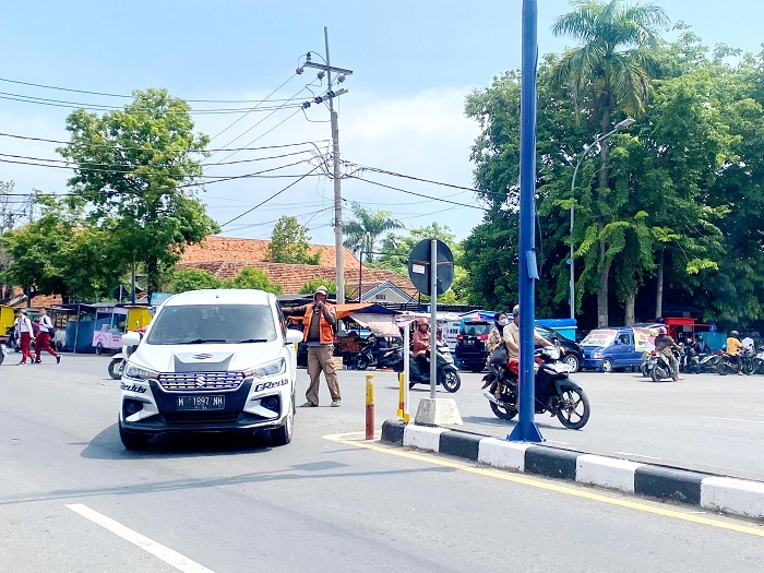 TERIK: Petugas parkir mengatur kendaraan yang hendak ke luar dari area parkir toko modern di Jalan Trunojoyo Sampang Selasa (9/1). (MOH. IQBAL AFGANI/JPRM)