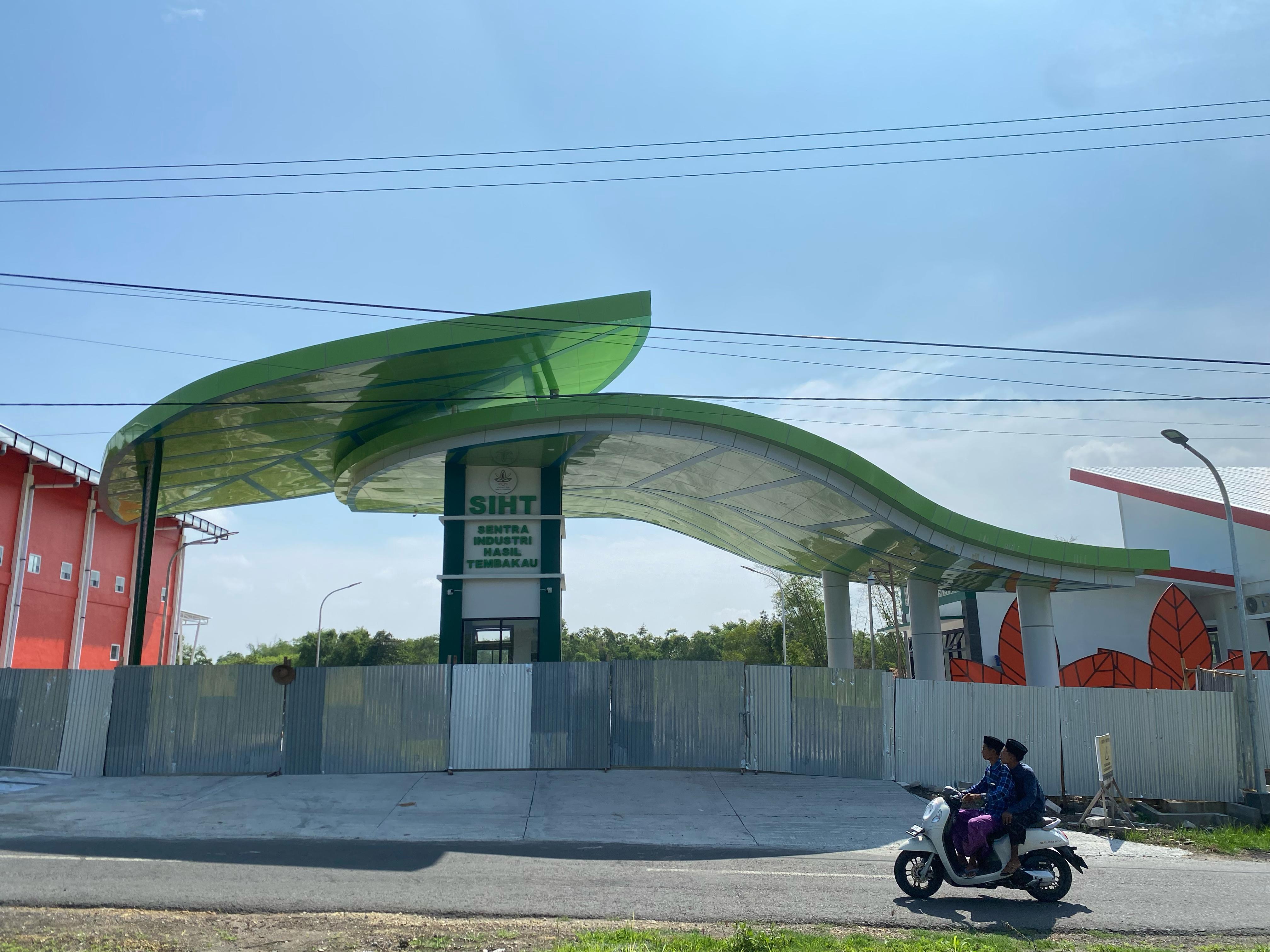 BELUM SELESAI: Warga melintas di depan bangunan sentra industri hasil tembakau (SIHT) di Desa Gugul, Kecamatan Tlanakan, Rabu (10/1). (MOH. JUNAIDI/JPRM)