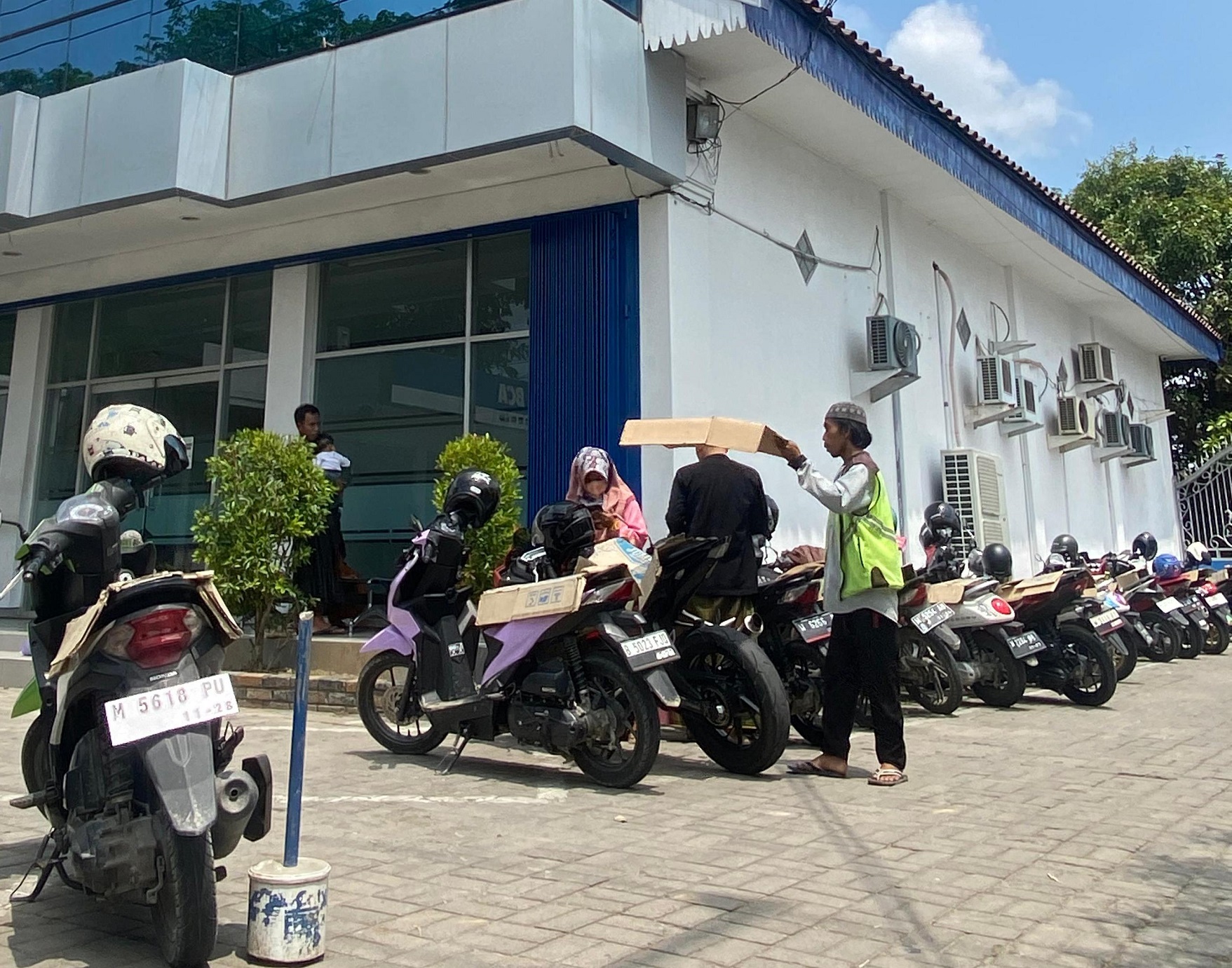 TERIK: Juru parkir mengatur kendaraan yang keluar masuk di salah satu ATM di Jalan KH. Wahid Hasyim Sampang Rabu (10/1). (MOH. IQBAL AFGANI/JPRM)