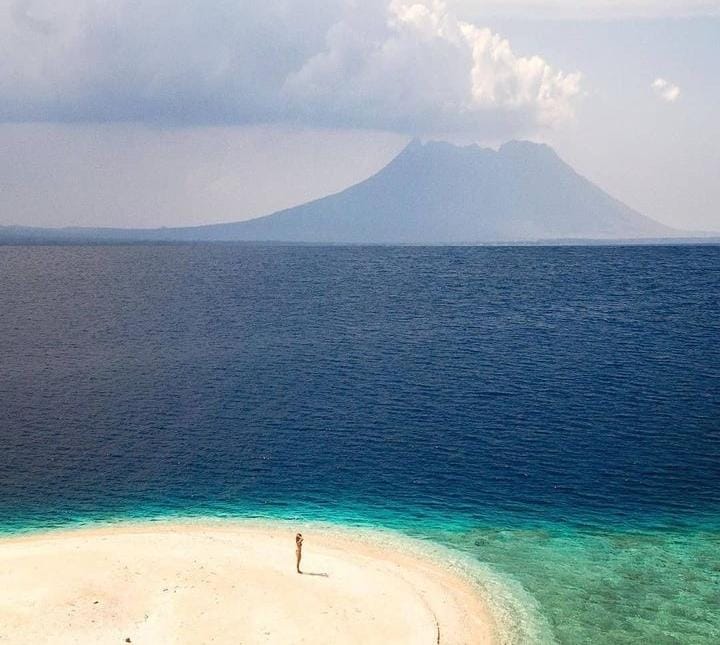 Keindahan pantai Pulau Tabuhan yang dihiasi pasir putih bersih serta pemandangan gunung Ijen yang bisa dinikmati dari kejauhan. (@liburanyuk.co untuk RadarMadura.id)