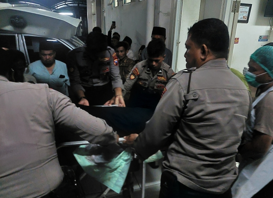 KAWAL KETAT: Petugas keamanan Polres Bangkalan mengeluarkan mayat korban dari ambulan di RSUD Syamrabu Bangkalan pada Jumat (12/1) malam.