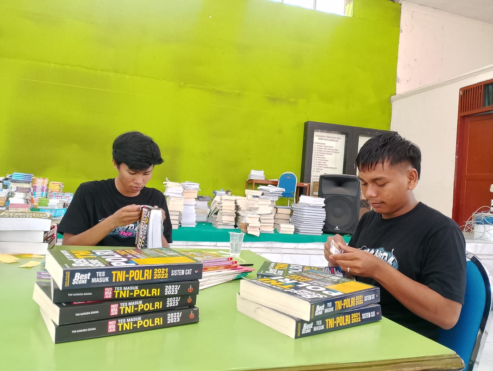 SIBUK: Pemuda memasang label buku milik Dispusip Pamekasan di Gedung Pemuda, Jalan Kabupaten, Pamekasan, Rabu (17/1). (UBAIDILLAHIR RA&rsquo;IE/JPRM)
