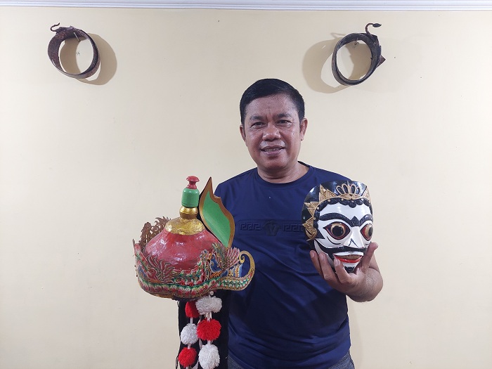 KONSISTEN: Sudarsono berpose bersama topeng di Sanggar Tarara, Bangkalan, Selasa (9/1). (ZEINAL ABIDIN/JPRM)