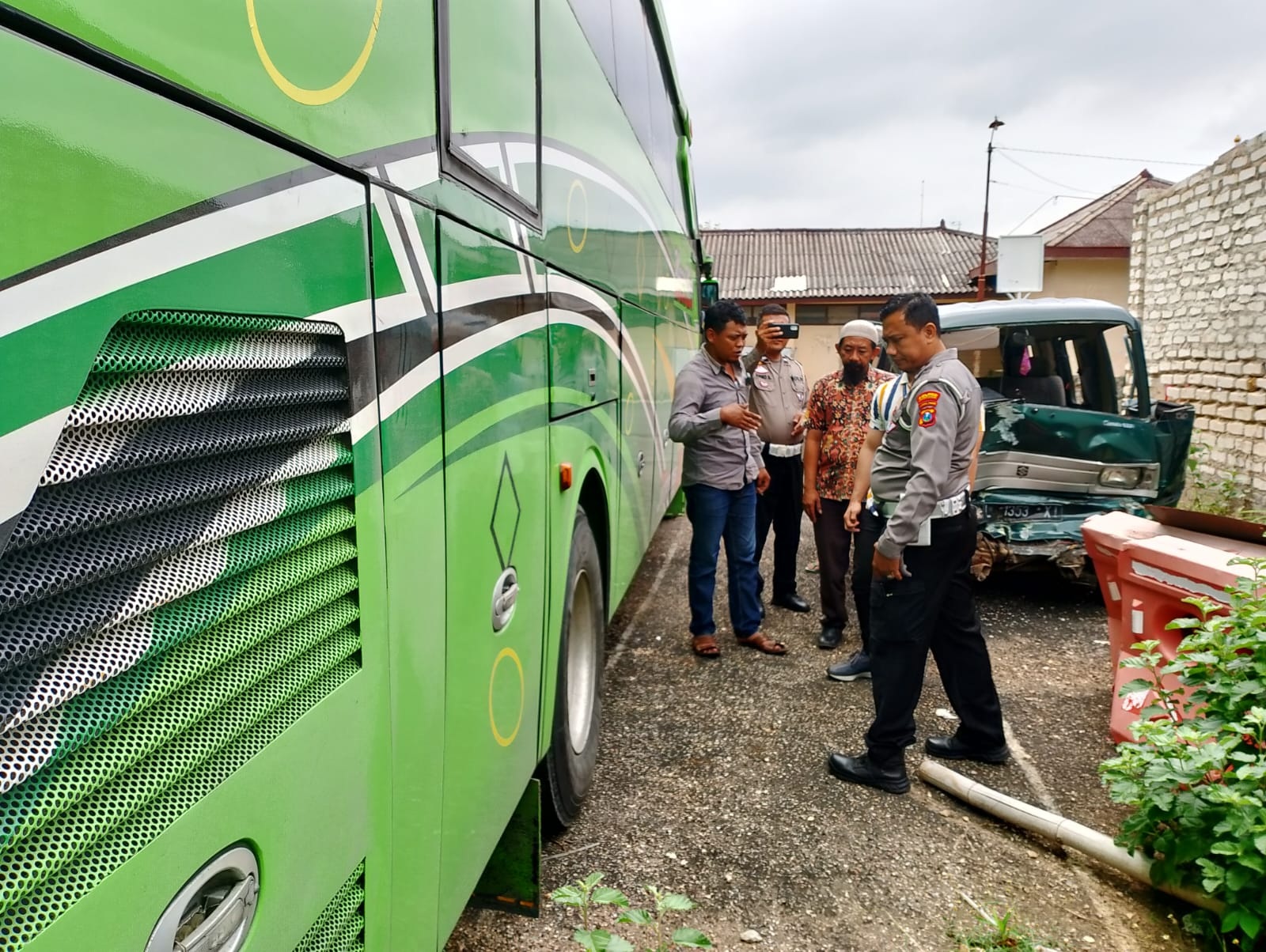 TERLIBAT LAKA: Anggota Polres Pamekasan bersama Susandi (kemeja abu-abu) memantau bus W 7420 UP yang melindas pengendara motor di kantor Satlantas Polres Pamekasan, Jumat (19/1).