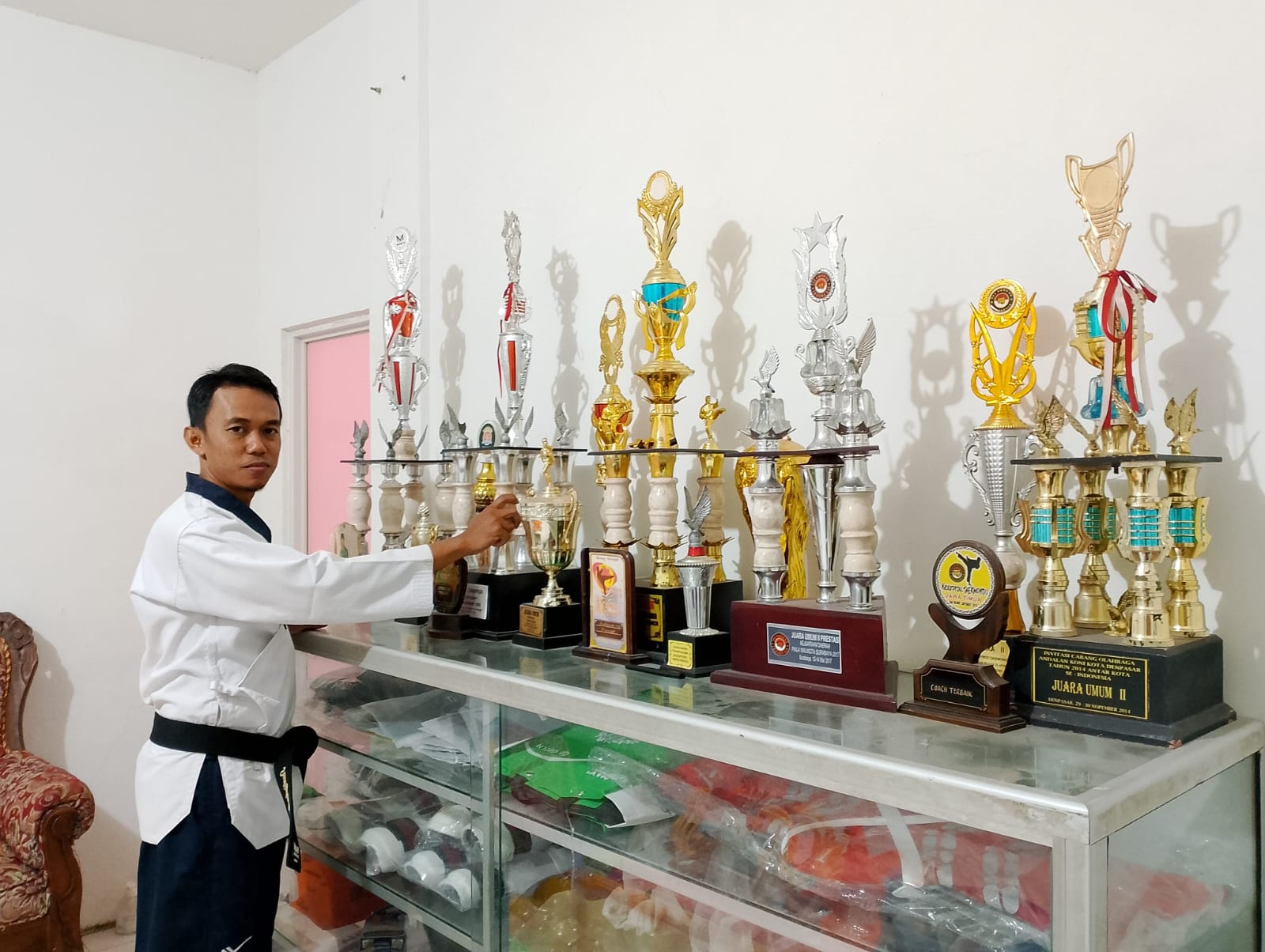 BERJEJER: Sudiyanto menunjukkan piala yang diperoleh atletnya di kejuaraan internasional, nasional, dan kejuaraan provinsi di ruang asrama atlet, Desa Bettet, Kecamatan Kota Pamekasan, Rabu (10/1).
