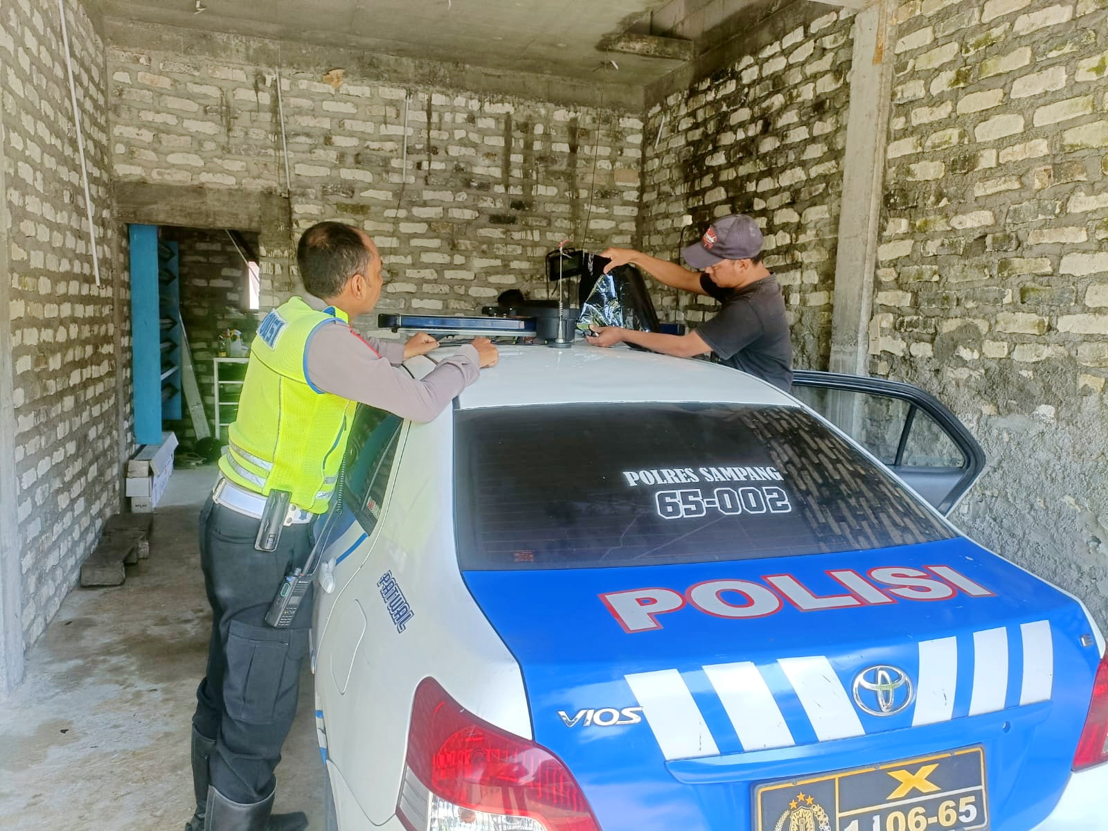 ATURAN BARU: Petugas Polres Sampang menutup bagian belakang lampu strobo atau rotator kendaraan dinas polisi. (SATLANTAS UNTUK JPRM)