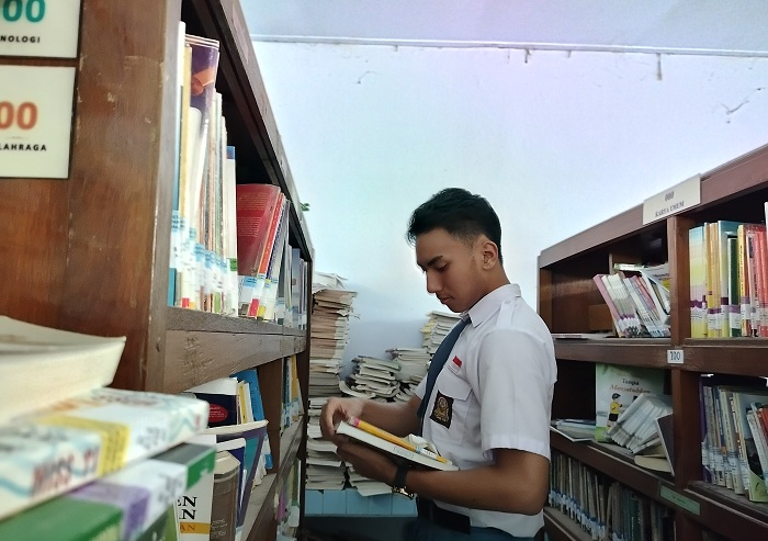BACA: Siswa SMAN 1 Pamekasan Rajendra Ammar Bakhtiar saat mencari buku di perpustakaan sekolah, Kamis (25/1). (LAILIYATUN NURIYAH/JPRM)