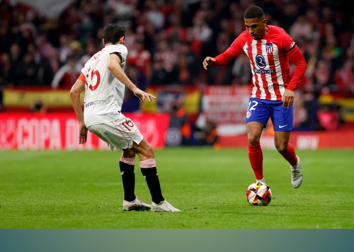 Pemain Atletico menggiring bola dan dibayangi pemain Sevilla