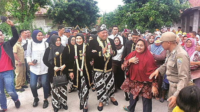 DISAMBUT HANGAT: Bupati Sampang Slamet Junaidi (berkalung melati) bersama istri, Hj Mimin Haryati, menyapa warga saat menuju kediaman pribadinya di Kelurahan Karang Dalem, Kota Sampang, Senin (29/1).