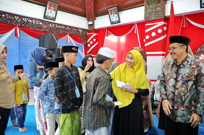 PEDULI: Ketua TP PKK Sampang Mimin Hariyati (kerudung kuning) didampingi Kepala Dinsos PPPA Edi Subinto (pakai kacamata) menyalurkan santunan anak yatim di Pendopo Kabupaten Sampang, Minggu (28/1).
