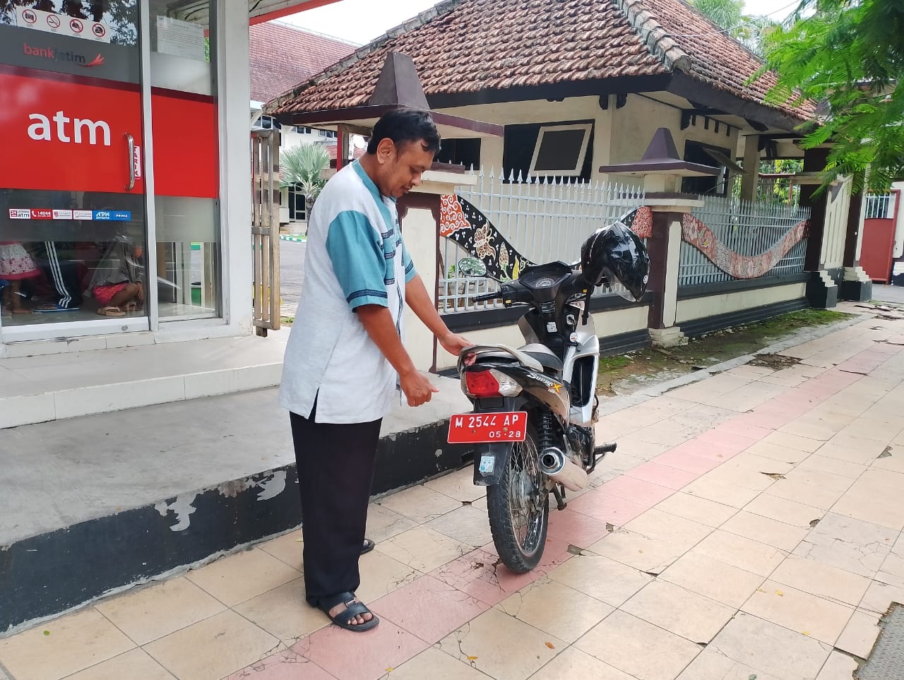 LENGANG: Warga menunjukkan stiker parkir berlangganan yang terpasang di kendaraannya di Jalan Kabupaten, Pamekasan, Jumat (2/2). (UBAIDILLAHIR RAIE/JPRM)