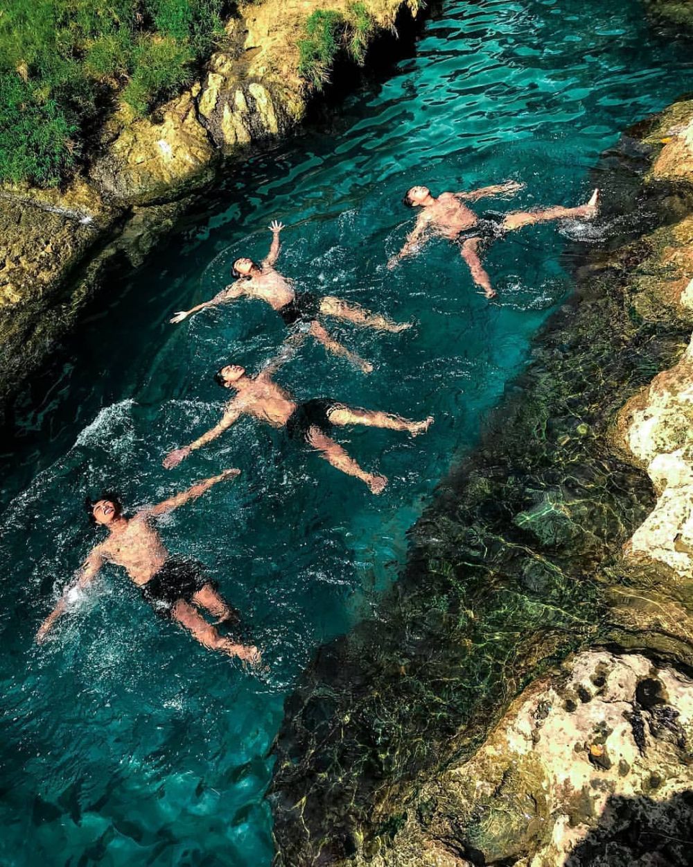 Terdapat empat wisatawan tengah berenang di Sumber Mata Air Krawak