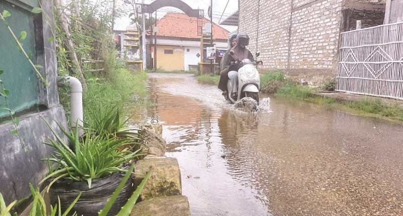 WASPADA: Pengendara melewati jalan yang tergenang air di Jalan Rajawali I, Kelurahan Karang Dalem, Kecamatan Kota Sampang, Selasa (6/2). (JUNAIDI PONDIYANTO/JPRM)