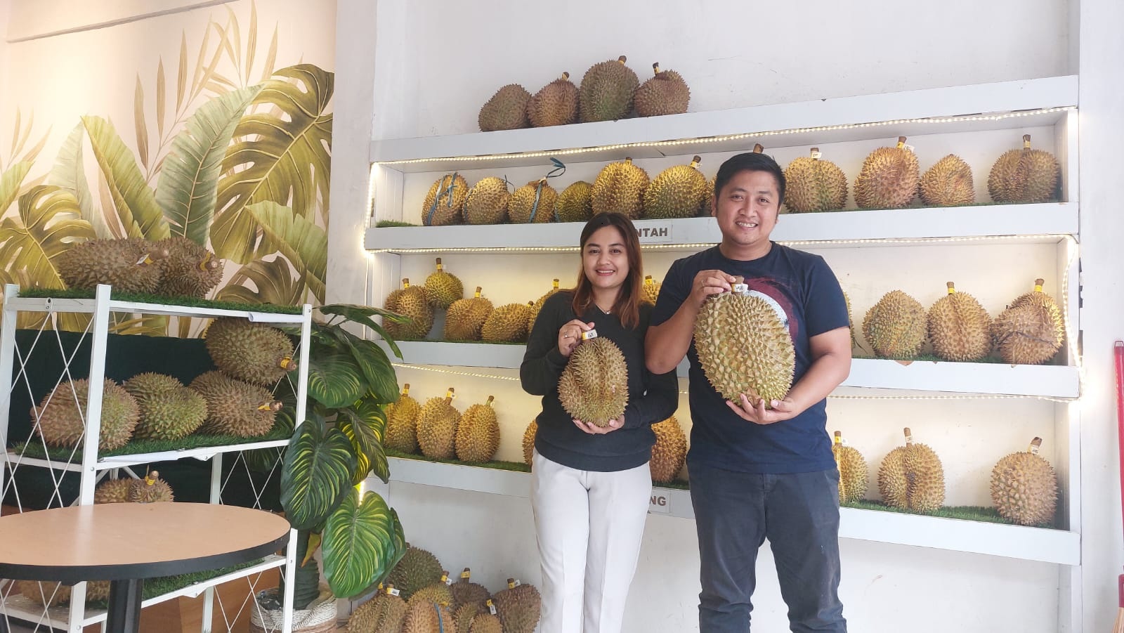 SERASI: Pemilik Outlet Durian PJ Agung Noviandri Kurniawan bersama istrinya, Ani Dian Putri, menunjukkan durian di toko di Jalan KH Wahid Hasim, Kota Sampang, Rabu (7/2). (JUNAIDI PONDIYANTO/JPRM)