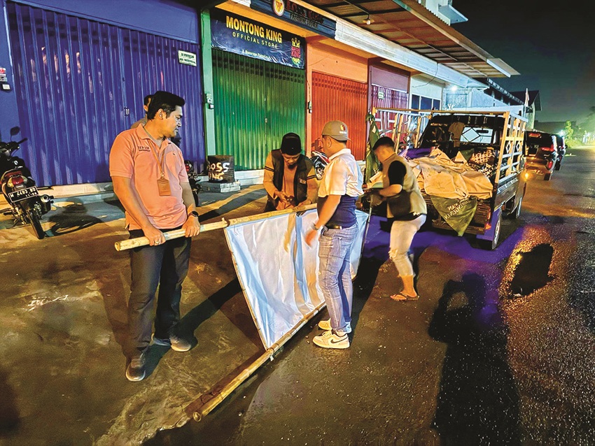 HARI TENANG: Anggota Bawaslu Pamekasan menurunkan alat peraga kampanye milik kontestan pemilu di Jalan Bonorogo, Kabupaten Pamekasan, dini hari Minggu (11/2). (BAWASLU UNTUK JPRM)