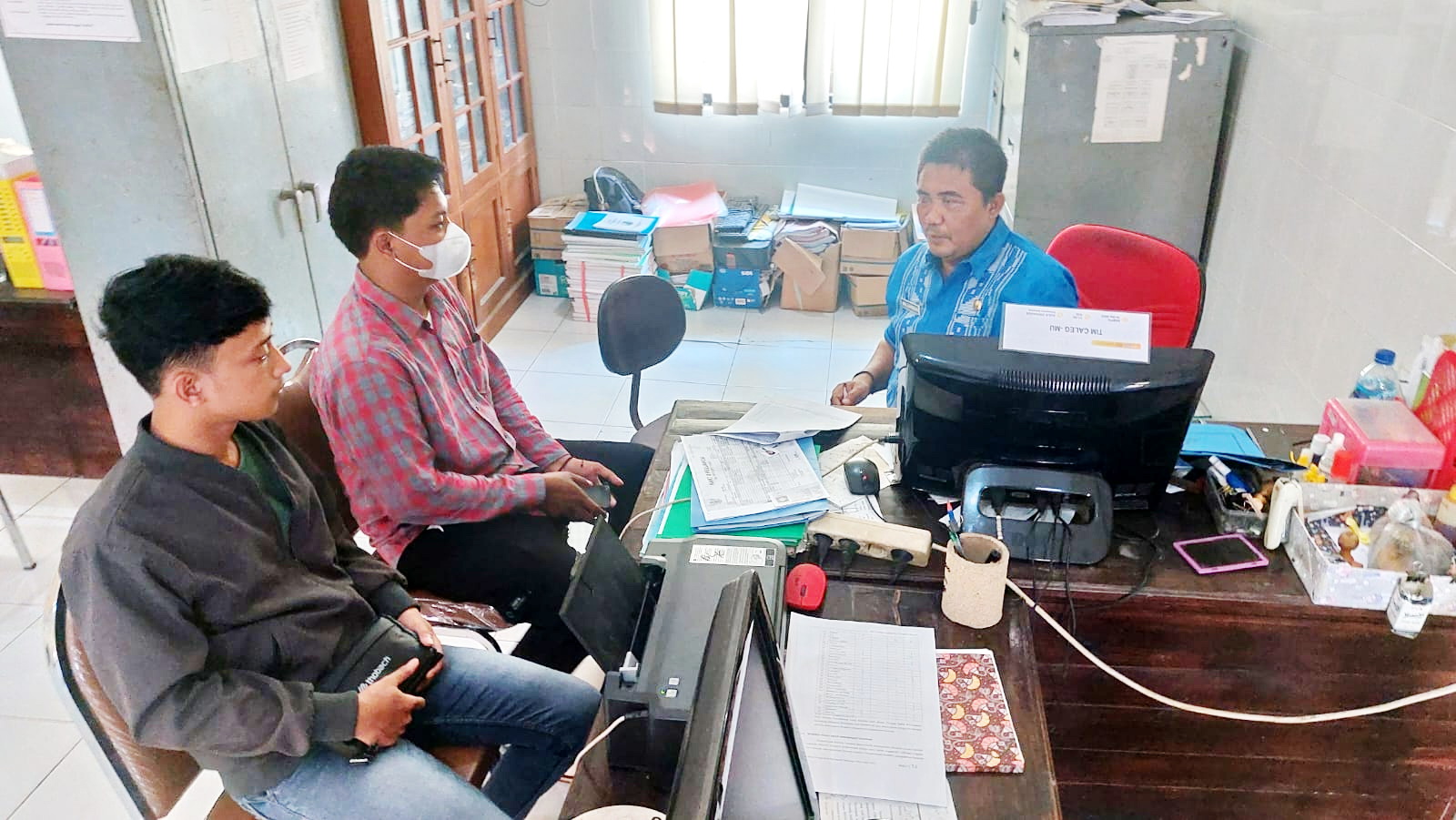 RAMAH: Pegawai Dinas Tenaga Kerja Sampang Moh. Zainuddin (kanan) melayani warga yang mengurus dokumen pengajuan menjadi PMI di kantornya, Jumat (16/2). (JUNAIDI PONDIYANTO/JPRM)