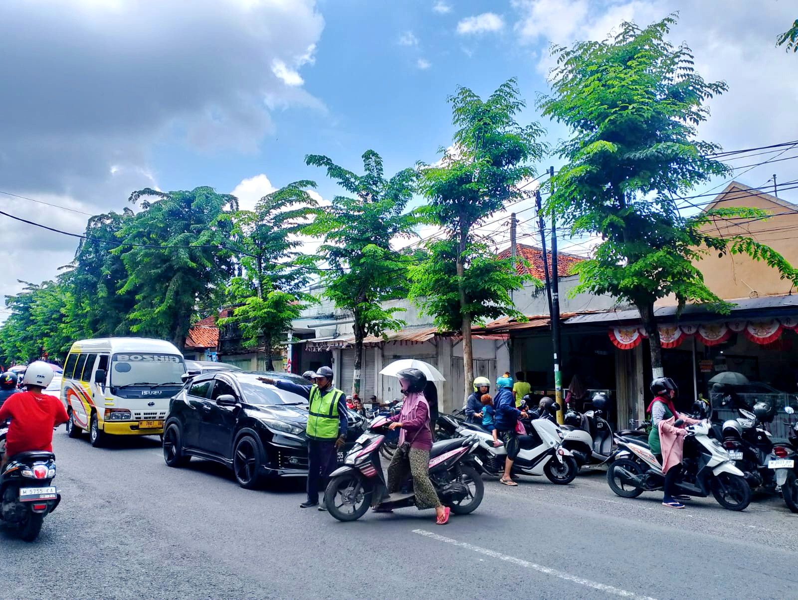 KAWASAN PARKIR BERLANGGANAN: Jukir mengawal kendaraan saat hendak melintas di Jalan Diponegoro, Kecamatan Pamekasan, Senin (19/2). (UBAIDILLAHIR RA&rsquo;IE/JPRM)