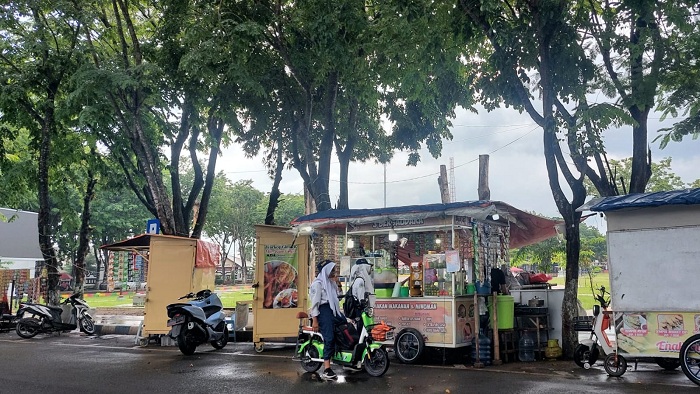PEDAGANG KECIL: Siswa sedang membeli minuman di pedagang kali lima yang membuka lapaknya di sepanjang Jalan Wijaya Kusuma, Kota Sampang, Senin (19/2). (JUNAIDI PONDIYANTO/JPRM)