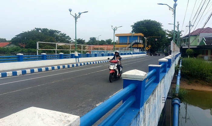 SARANA PENYEBERANGAN: Seorang warga melintas di atas jembatan yang berada di Jalan Bahagia, Kota Sampang, Rabu (21/2). (JUNAIDI PONDIYANTO/JPRM)
