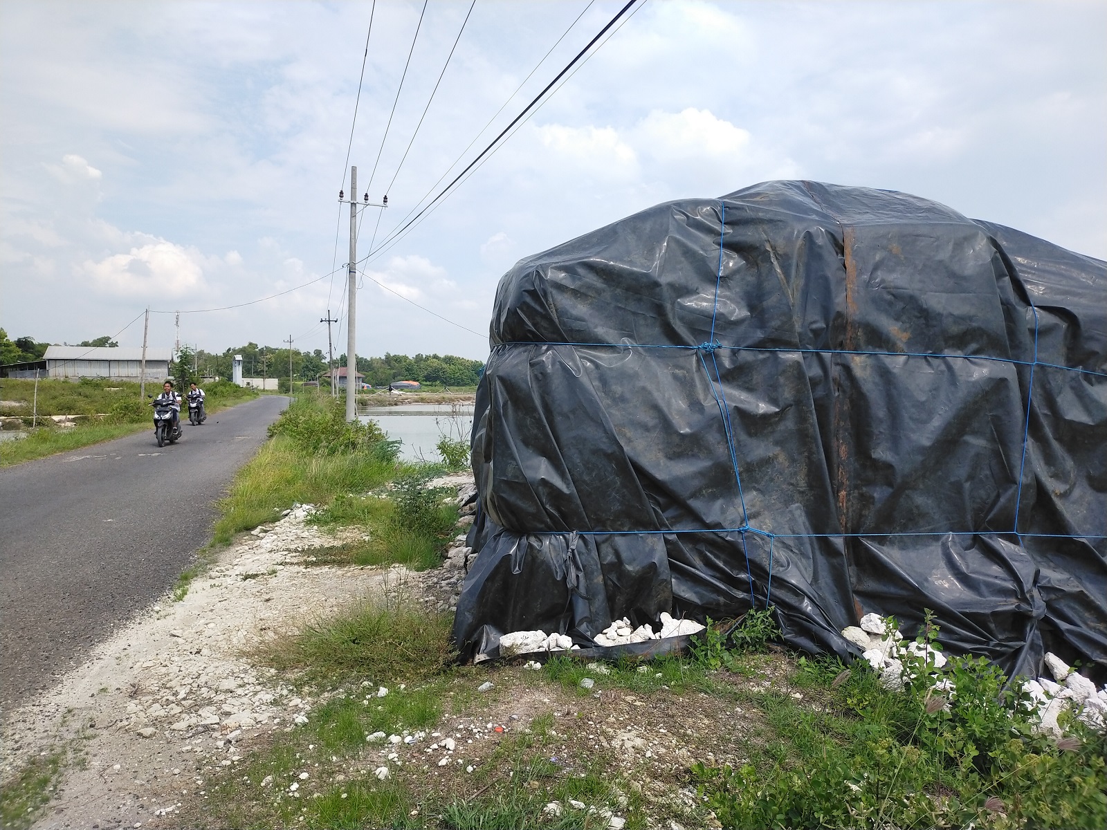 TARGET PRODUKSI NAIK: Siswa mengendarai sepeda motor di dekat tumpukan garam yang ditutup geomembran di Desa Gili Barat, Kecamatan Kamal, Bangkalan, Senin (26/2). (VIVIN AGUSTIN HARTONO/JPRM)