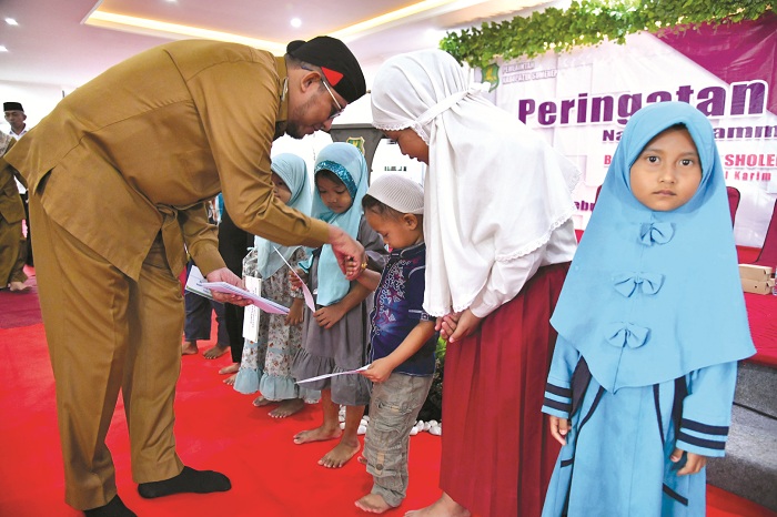 PEDULI: Bupati Sumenep Achmad Fauzi Wongsojudo memberikan santunan kepada anak yatim dalam acara Isra Mikraj di Gedung Islamic Center, Batuan, pada Senin (26/2). (HUMAS PEMKAB SUMENEP UNTUK JPRM)