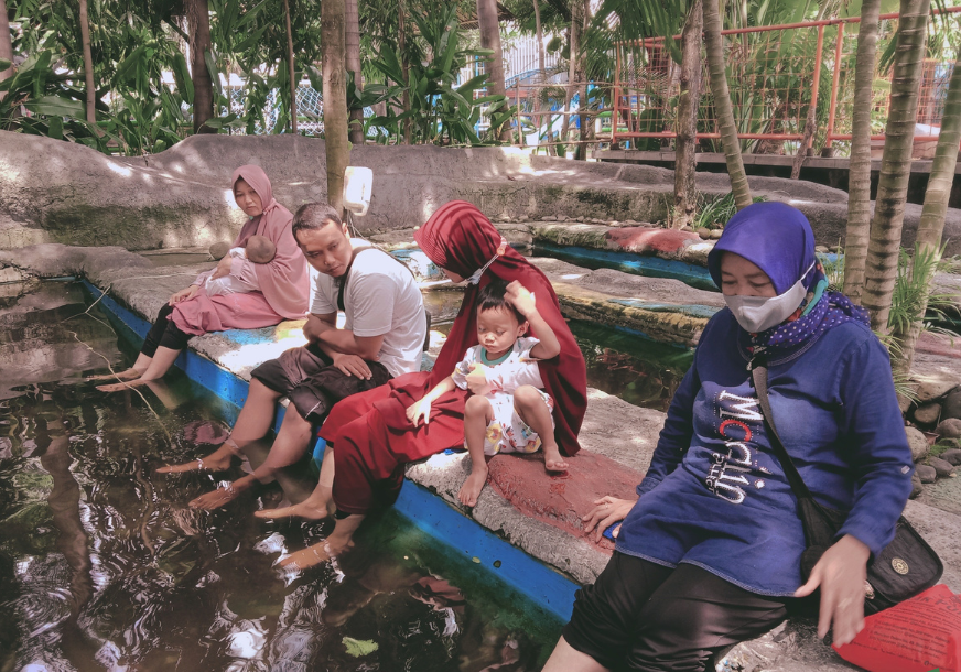 Pengunjung menikmati terapi ikan di Legok Asri Park