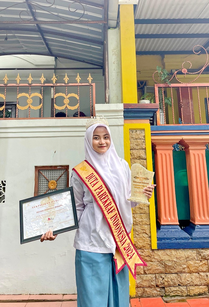 PRESTASI: Revani memegang piagam penghargaan dan vandel Duta Parekraf Indonesia 2024 di kediamannya di Jalan Lawangan Daya, Perumahan Bonorogo Permai K-16, Pademawu, Pamekasan, Kamis (29/2).