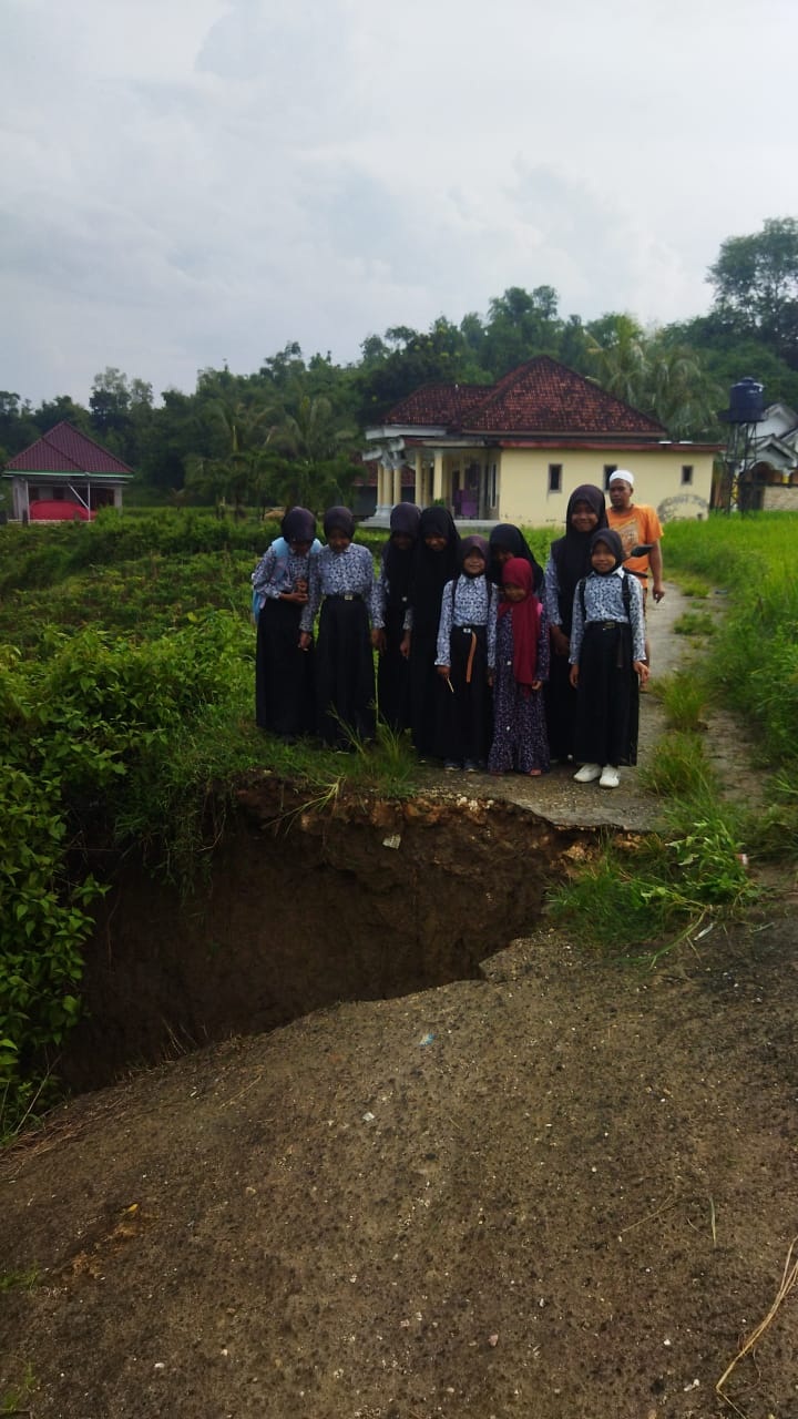 RUSAK: Pelajar mengamati jalan yang ambles di Desa Bujur Timur, Kecamatan Batumarmar, Kamis (7/3). (SAMHADI UNTUK JPRM)